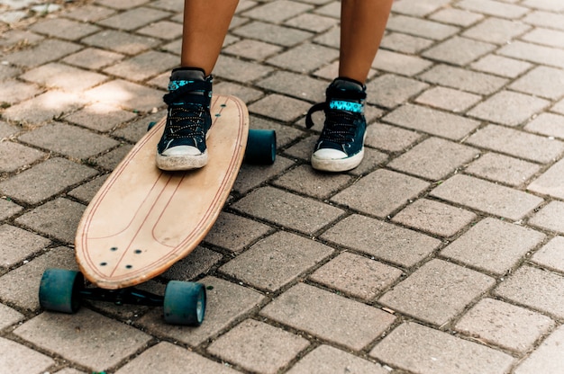 La gamba della ragazza in scarpe da ginnastica in piedi su uno skateboard.