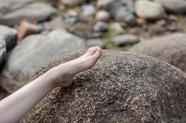 La gamba femminile nuda giace su una grande pietra