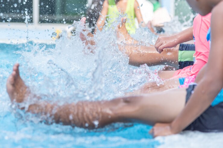 La gamba ha sparato del bambino alla classe della piscina che impara nuotare