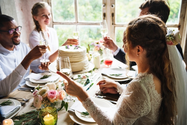 La gente aderisce ai vetri di vino sul ricevimento nuziale con la sposa e lo sposo