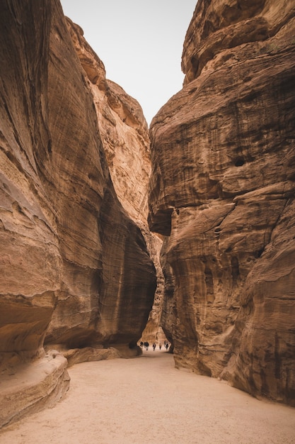 La gente cammina nella stretta gola del Siq nelle montagne sabbiose e desertiche, in Giordania, nella città di Petra