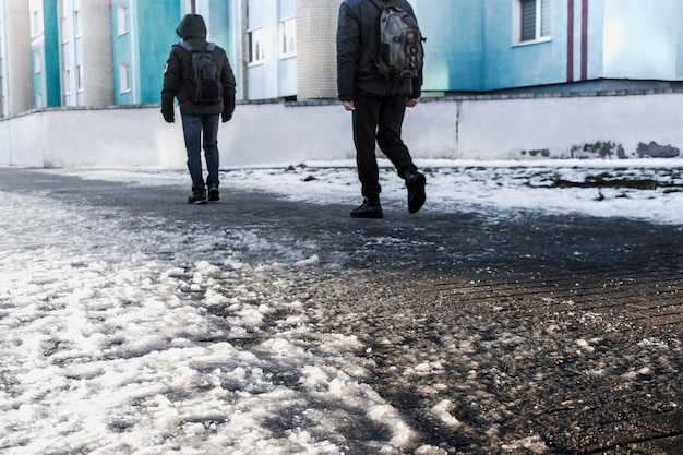 La gente cammina su una strada scivolosa fatta di ghiaccio fuso Vista delle gambe di un uomo che cammina su un marciapiede ghiacciato Strada invernale in città Infortunio dopo una caduta su una strada ghiacciata