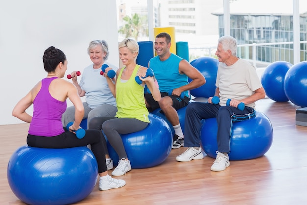 La gente che alza i dumbbells nella classe della palestra