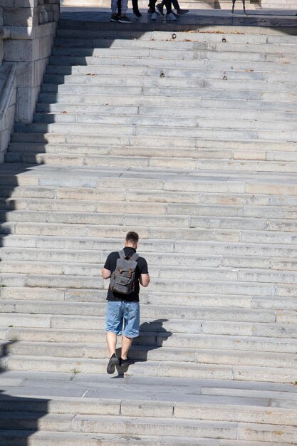 La gente che cammina dalle scale di pietra con la giornata di sole dello zaino