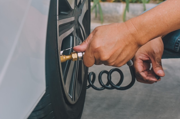 La gente che gonfia le gomme dell'auto parcheggiata