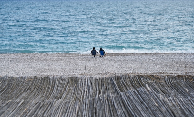 La gente seduta pacifica in riva al mare