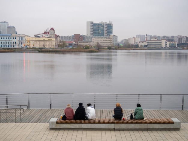 La gente si siede su una panchina in un giorno d'autunno e ammira la superficie del lago
