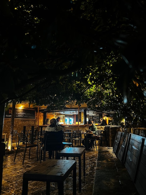 La gente si siede sulle sedie di un caffè di strada alla luce delle lanterne di notte