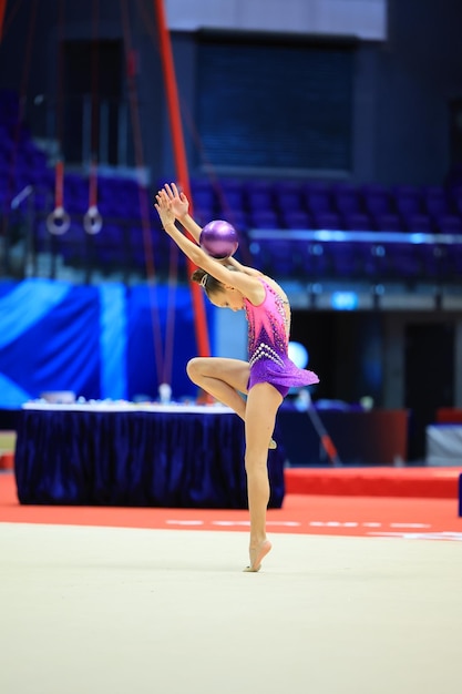 La ginnasta della bambina esegue vari esercizi di ginnastica e fitness sul concetto di infanzia e