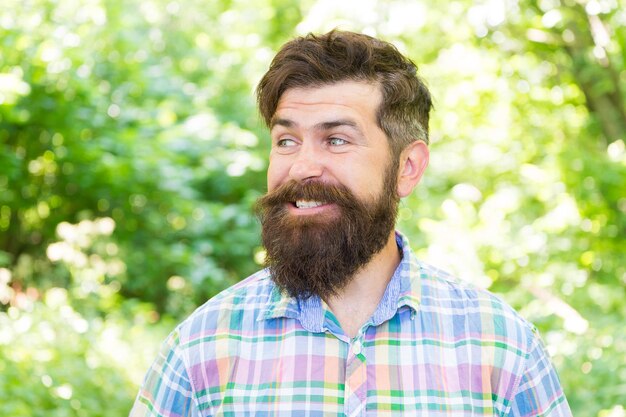 La gioia della migliore acconciatura. Uomo barbuto che sorride con l'acconciatura alla moda in estate. Felice hipster con acconciatura facciale alla moda. Ragazzo caucasico che indossa l'acconciatura di design all'aperto.