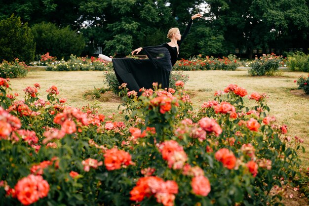 La giovane ballerina in vestito nero che posa e che mostra il balletto posa nel parco dell'estate