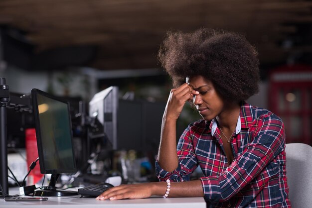 La giovane bella donna afroamericana di successo si sente stanca in un grande ufficio moderno