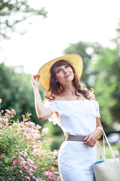 La giovane bella donna cammina nel parco fiorito. Ritratto di una giovane donna. Ragazza felice. Estate.