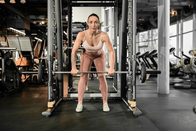 La giovane bella donna caucasica in forma forte sta facendo esercizi in palestra