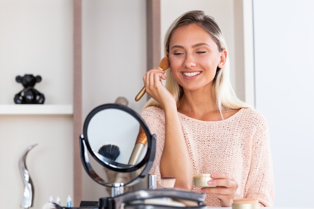 La giovane bella donna che la fa compone vicino allo specchio