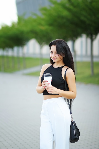 La giovane bella donna di affari beve il caffè vicino accanto all'edificio per uffici