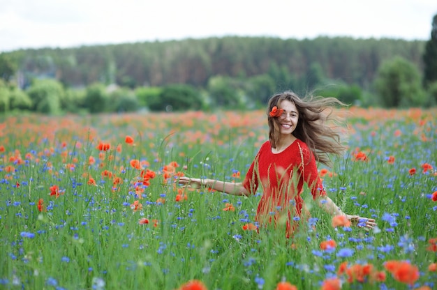 La giovane bella donna felice si diverte nel campo del papavero di primavera. Concetto di libertà e felicità estiva