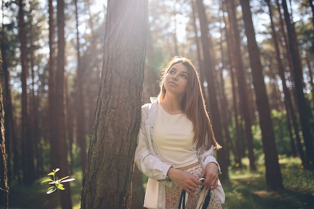 La giovane bella donna hippie cammina nella foresta estiva ride, balla e si gode la vita e la natura