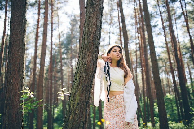 La giovane bella donna hippie cammina nella foresta estiva ride, balla e si gode la vita e la natura