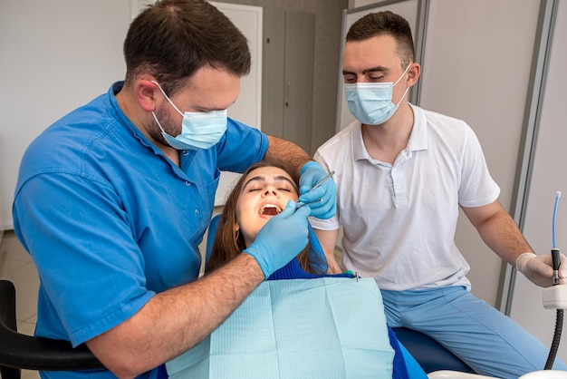 La giovane bella donna in tratta i suoi denti al concetto di stomatologia di assistenza sanitaria del dentista