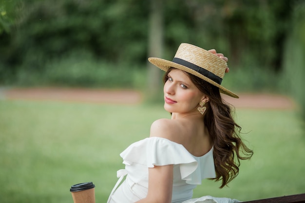 La giovane bella donna incinta beve il cappuccino nel parco