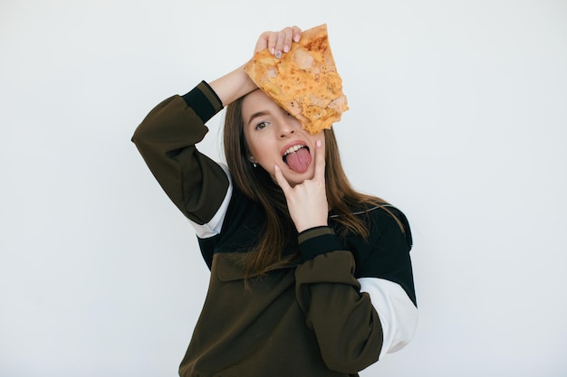 La giovane bella donna mangia la fetta di pizza ai peperoni