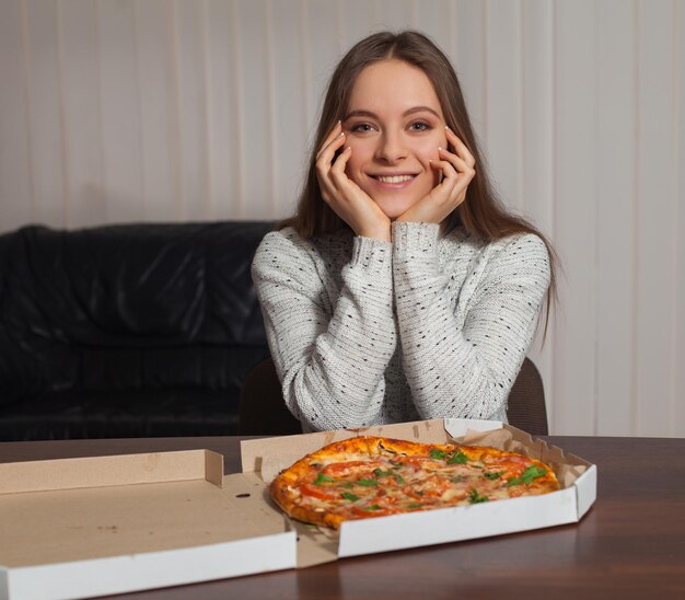 La giovane bella donna sorride perché ha la pizza per cena