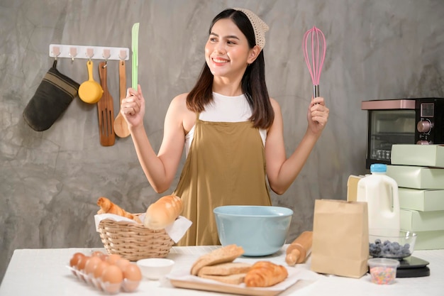 La giovane bella donna sta cuocendo nella sua attività di panetteria e caffetteria in cucina