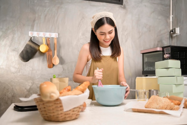 La giovane bella donna sta cuocendo nella sua attività di panetteria e caffetteria in cucina