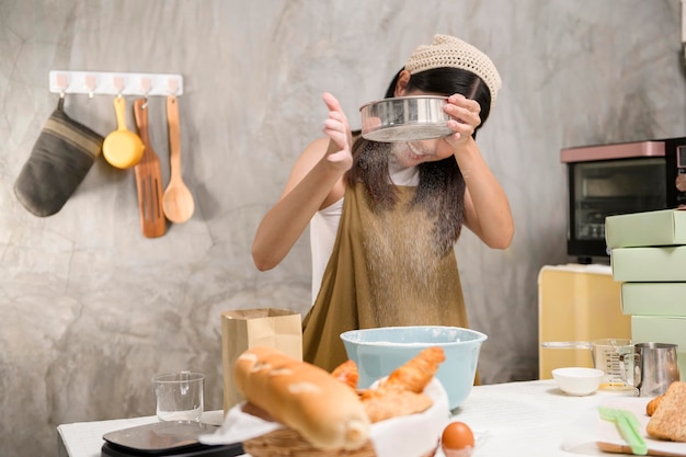 La giovane bella donna sta cuocendo nella sua attività di panetteria e caffetteria in cucina