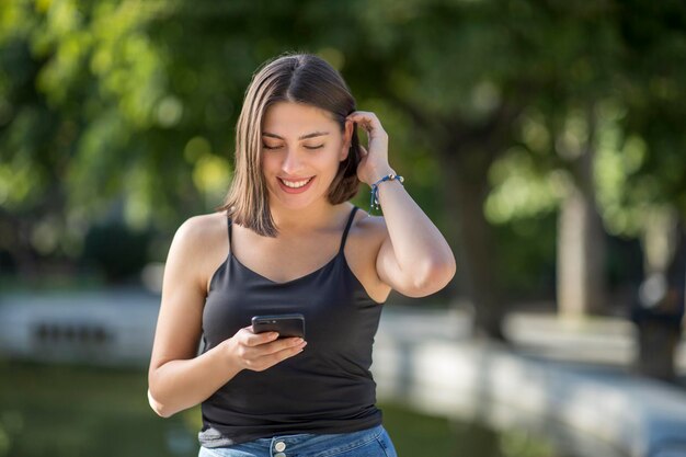 La giovane bella donna turca sta controllando il telefono cellulare mentre sorride