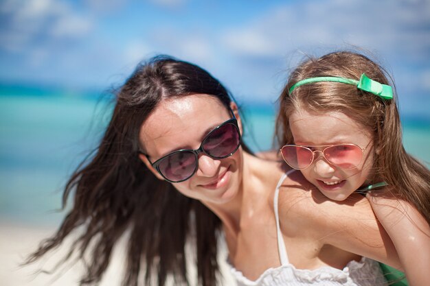 La giovane bella madre e la sua adorabile piccola figlia si divertono in spiaggia tropicale