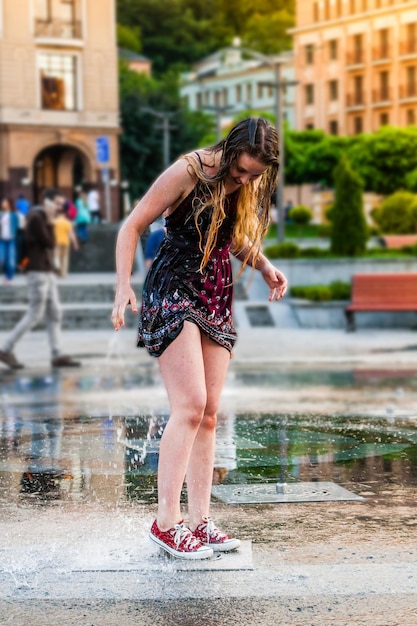 La giovane bella ragazza balla in una fontana