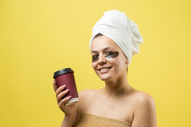 La giovane bella ragazza in un asciugamano bianco sulla testa indossa cerotti in gel di collagene sotto gli occhi Maschera sotto il viso per il trattamento degli occhi