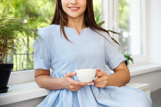 La giovane bella signora caucasica gode di bere il caffè