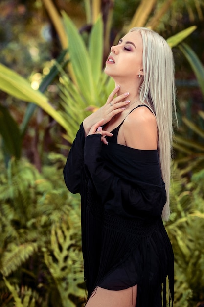 La giovane bionda di lusso in una camicia nera sta sorridendo alla macchina fotografica