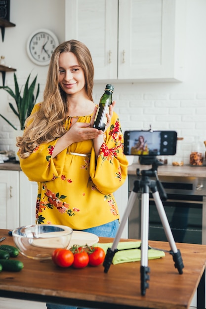 La giovane blogger di ragazza incinta abbastanza gira un video di una ricetta di insalata su una fotocamera dello smartphone