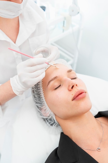 La giovane cliente del salone di cosmetica con una maschera per il viso pulente