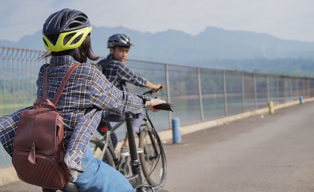 La giovane coppia asiatica va in bicicletta insieme al lavoro