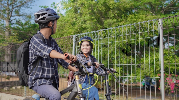La giovane coppia asiatica va in bicicletta insieme al lavoro