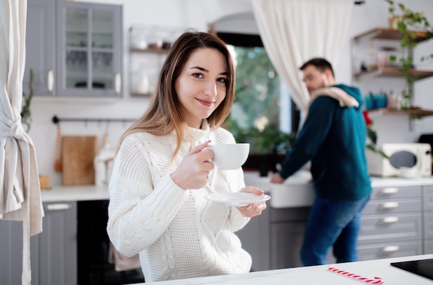 La giovane coppia di sposi beve il caffè in cucina