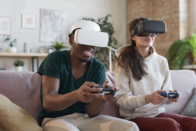 La giovane coppia è felice di giocare ai videogiochi che indossano occhiali virtuali nell'appartamento