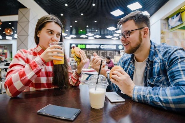 La giovane coppia fa una pausa per lo shopping mangiando hamburger nel bar del centro commerciale