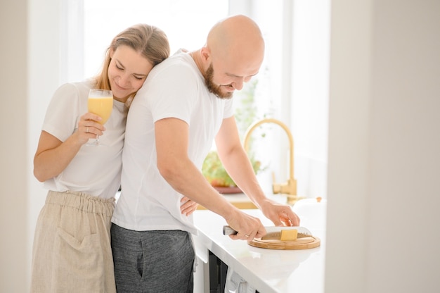 La giovane coppia felice prepara la colazione e si diverte a vicenda.