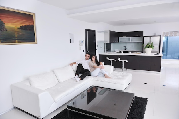 La giovane coppia felice si rilassa nel soggiorno di casa moderno al coperto