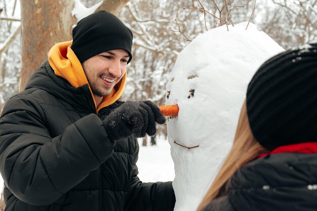 La giovane coppia ha fatto un pupazzo di neve in un parco innevato