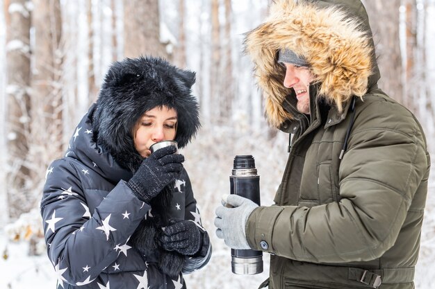 La giovane coppia innamorata beve una bevanda calda da un thermos e si gode la natura invernale