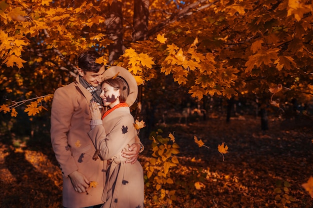 La giovane coppia nell&#39;amore cammina nella foresta di autunno fra le foglie cadenti