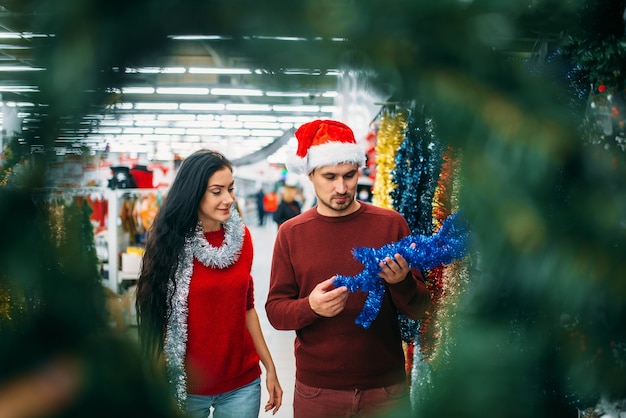 La giovane coppia osserva sulle decorazioni di festa nel supermercato