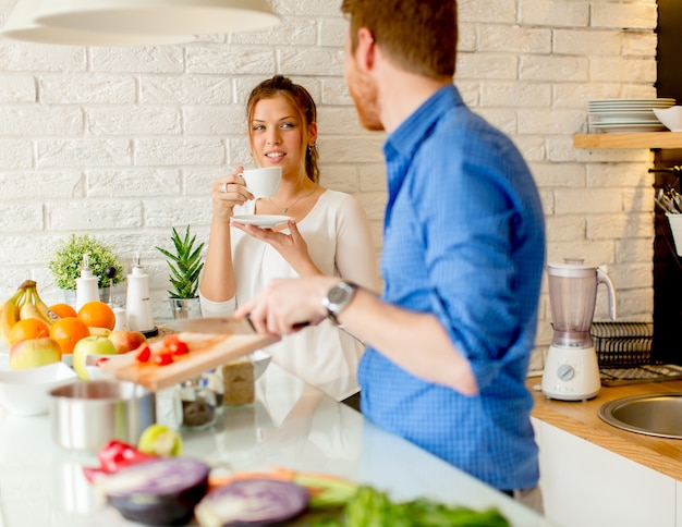La giovane coppia si diverte in cucina moderna al coperto mentre prepara verdure per il pranzo